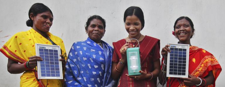 Women in India holding solar panels and smiling