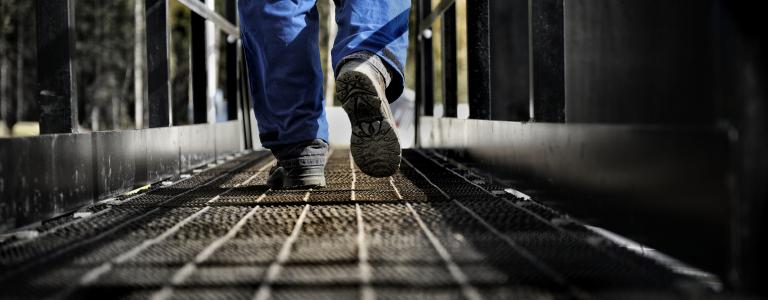 Worker walks along steel walkway.