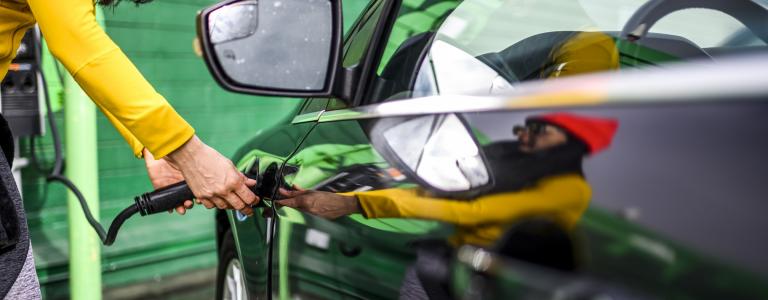 Woman in yellow sweater charging electric vehicle