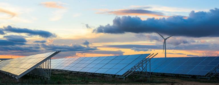 Solar panels and wind turbines against a cloudy sky