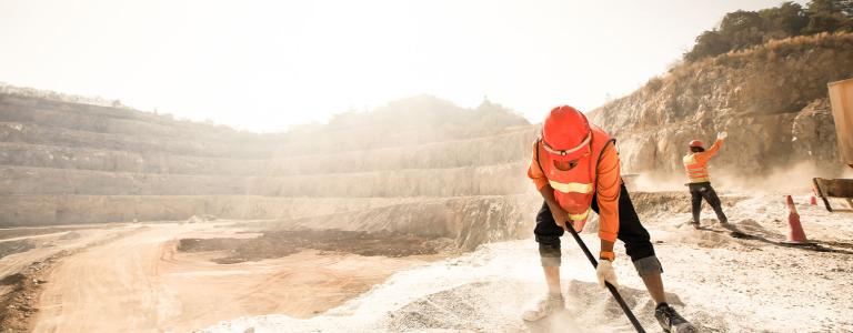 Miners working with mining tool under sun.