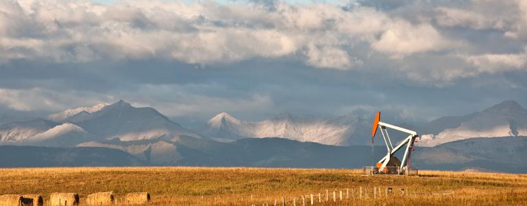 A pumpjack on the prairie. Alberta, Canada. Rocky Mountains in the distance.