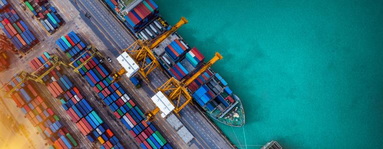 A ship unloads cargo at an industrial port near the water.