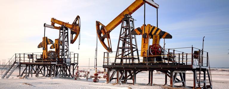 Two yellow-orange oil pumps stand against a snowy landscape.