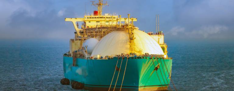 A green LNG ship travels across water off the coast of Senegal.