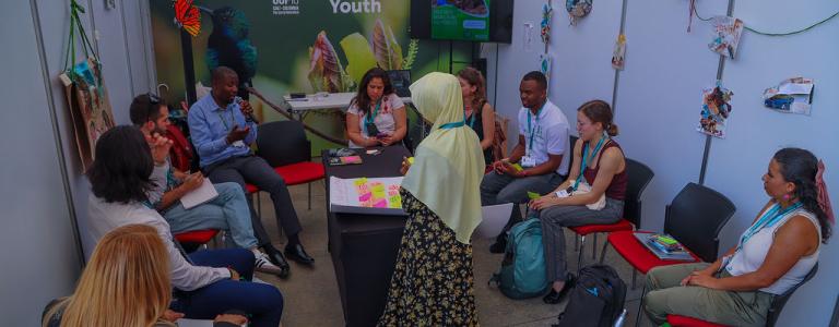 Young people from around the world sit in a small room at COP in Azerbaijan