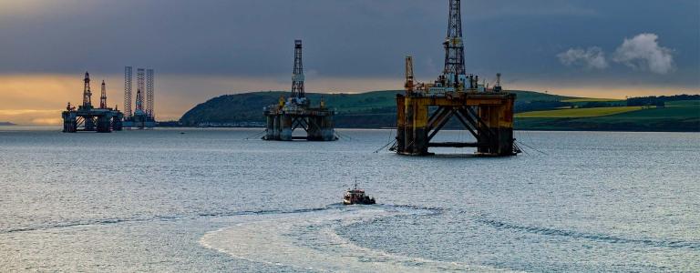 A fishing boat navigates water filled with offshore oil platforms