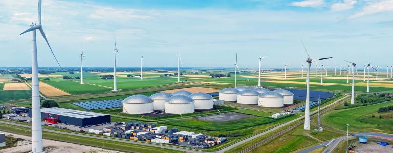 Wind turbines spin over an industrial site.
