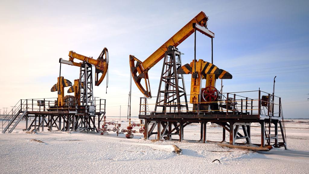 Two yellow-orange oil pumps stand against a snowy landscape.