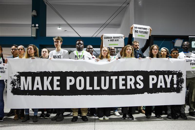 People holding a banner which says: "Make Polluters Pay!" at COP 29.