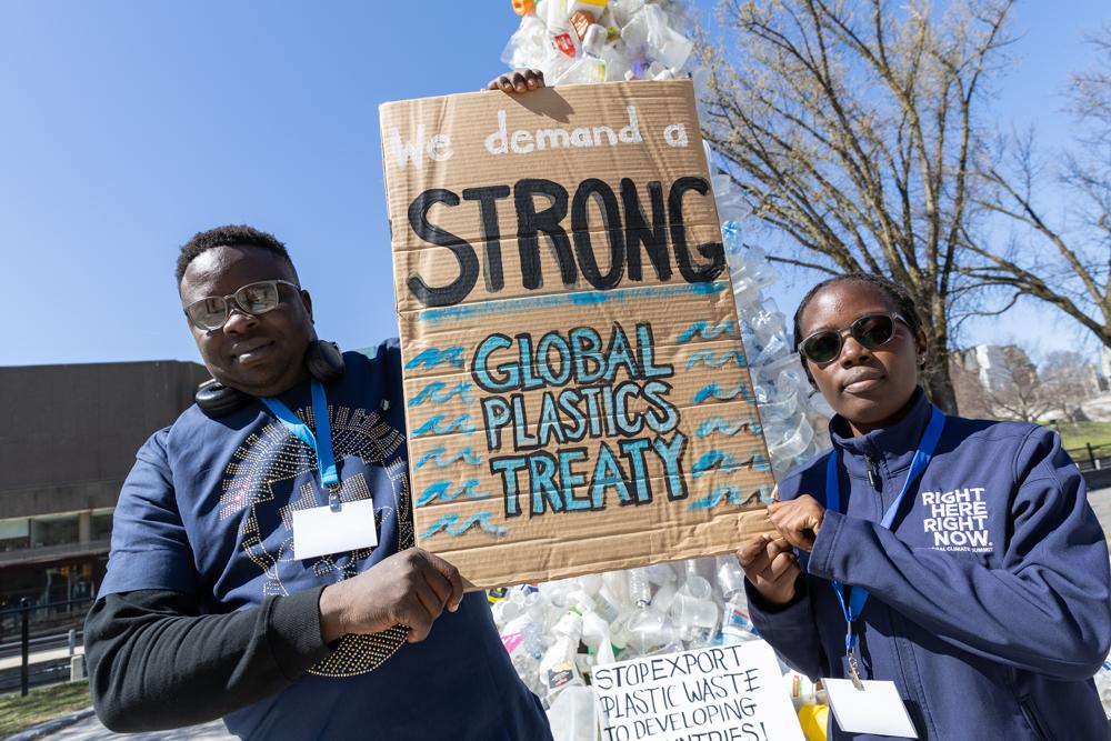 Two people hold a sign reading "we demand a strong global plastics treaty" at INC-4.