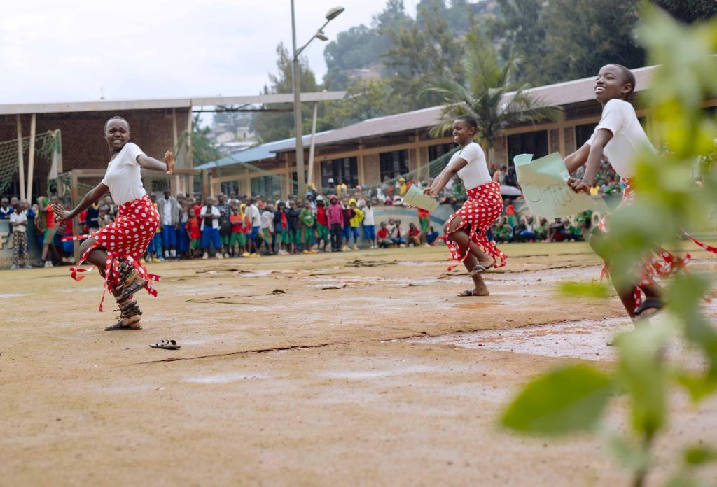 Three students perform a dance for a group of their peers.