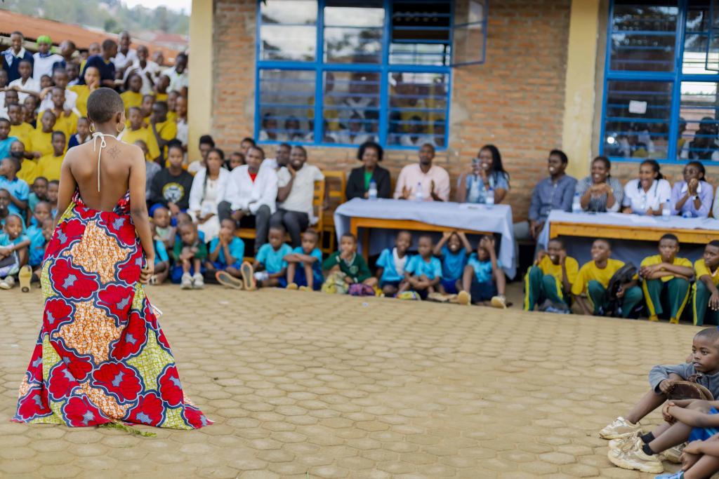 A student presents a dress to a group during a fashion show.
