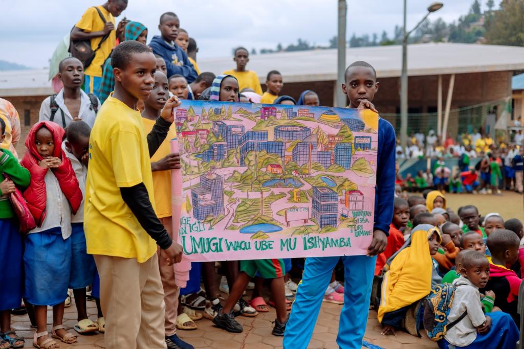 Two students present an artwork to a group of their peers. The piece depicts a city full of greenspace.